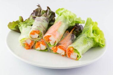 Beyaz arka planda beyaz bir tabakta salata rulo.