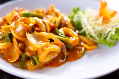 Ahşap bir masada beyaz tabakta kızarmış kalamar tuzlu yumurtası.