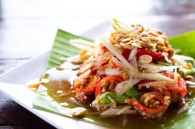 Ahşap bir masada beyaz bir tabak üzerinde Papaya salatası