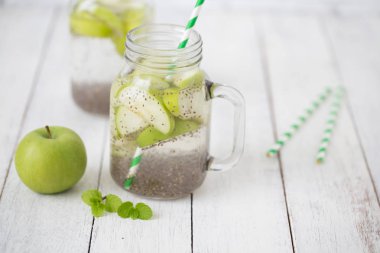 Elma yeşili dilimlenmiş cam içinde chia tohumları ve ahşap masada taze elmalar, sağlığa içelim.