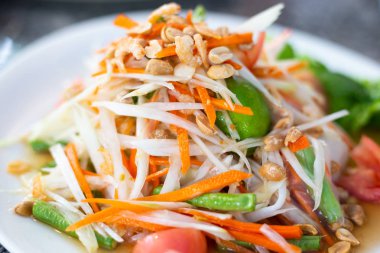 Ahşap bir masada beyaz bir tabak üzerinde Papaya salatası