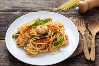 Ahşap bir masada baharatlı kızarmış karides ile Spagetti
