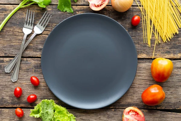 Tahta arka planda siyah tabakta spagetti. en üstteki görünüm