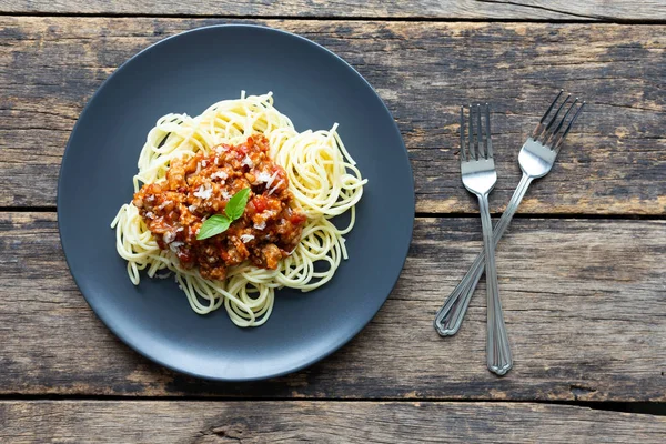 Tahta arka planda siyah tabakta spagetti. en üstteki görünüm