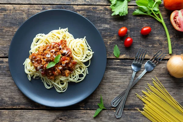 Tahta arka planda siyah tabakta spagetti. en üstteki görünüm