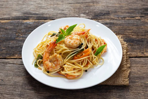 Ahşap bir masada baharatlı kızarmış karides ile Spagetti