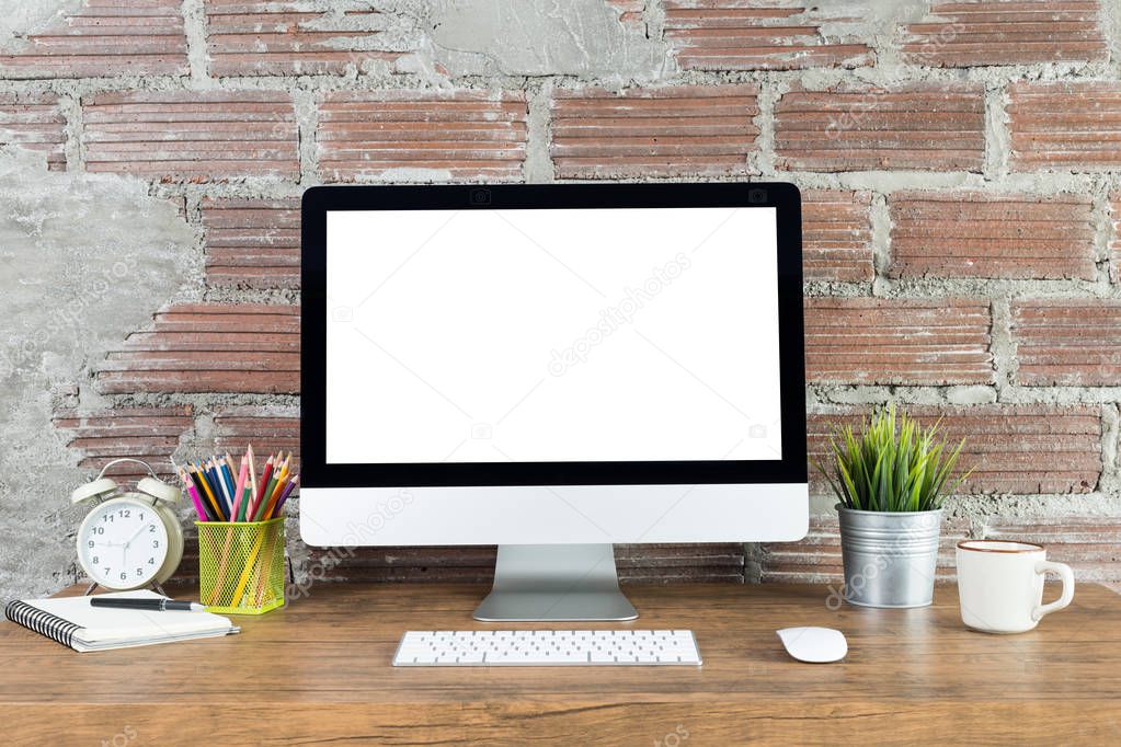 workspace with computer with blank white screen, and office supplies on a wooden desk