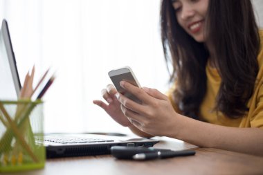 akıllı telefon ve dizüstü bilgisayar kullanarak evden çalışan genç kadın 