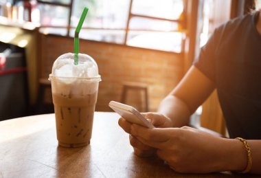 Kahve dükkanında ahşap masada akıllı telefon kullanan el kadını. 