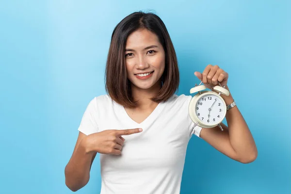 Retrato de confusa asiática joven sosteniendo alarma reloj isolat —  Fotos de Stock