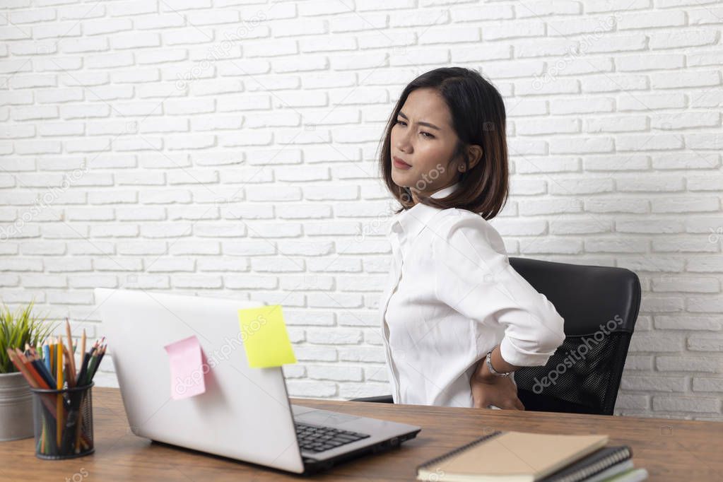 Business woman suffering from back pain in office home