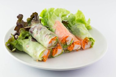 Beyaz arka planda beyaz bir tabakta salata rulo.