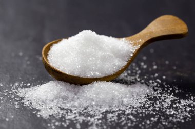 Tahta kaşıktaki şeker siyah bir arka plan üzerine