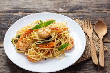 Ahşap bir masada baharatlı kızarmış karides ile Spagetti