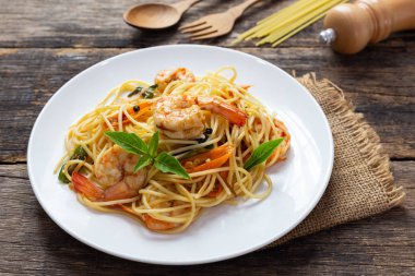 Ahşap bir masada baharatlı kızarmış karides ile Spagetti
