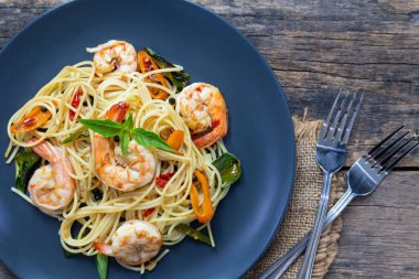 Ahşap bir masada baharatlı kızarmış karides ile Spagetti