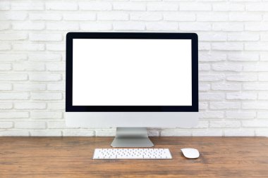 Boş beyaz ekranlı bilgisayar, çalışma alanı ve ahşap bir masada ofis malzemeleri.