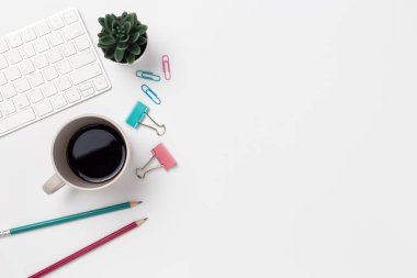 Üst manzara, çalışma masası, beyaz arka planda kahve ve ofis malzemeleri.