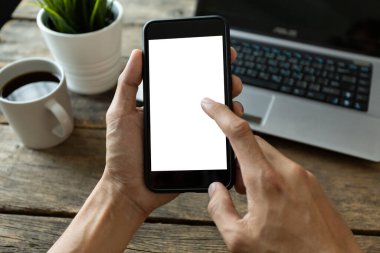 Elçi telefon kullanıyor, boş ekran akıllı telefon ve bilgisayar ahşap masa manzaralı. kırpma yolu ile