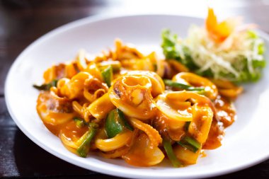 Ahşap bir masada beyaz tabakta kızarmış kalamar tuzlu yumurtası.