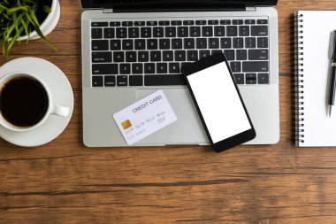 Masasında beyaz ekran, bilgisayar laptopu ve kredi kartı olan en iyi model akıllı telefon.