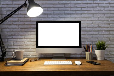 Boş beyaz ekran maketi ve ahşap masa üzerinde ofis malzemeleri olan çalışma alanı.