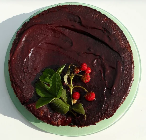 chocolate cake with chocolate icing decorated with a sprig of natural strawberries