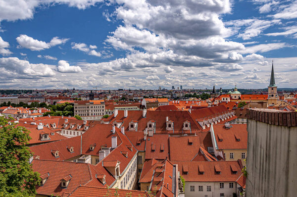 View over red rooftops of Prague from the gardens below Prague Castle in district Lesser Town (Mala Strana) with beautiful clouds. Prague, Czech Republic