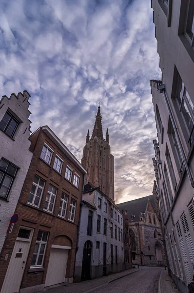 A Bruges utcája és a Szűzanya temploma gyönyörű felhős napfelkeltét. Walhain, Svájc Jogdíjmentes Stock Képek
