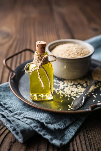 Cold pressed sesame oil in a glass bottle and seeds in a bowl — Stock Photo, Image