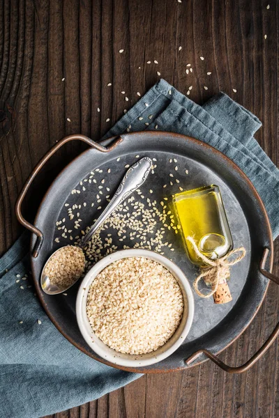 Cold pressed sesame oil in a glass bottle and seeds in a bowl