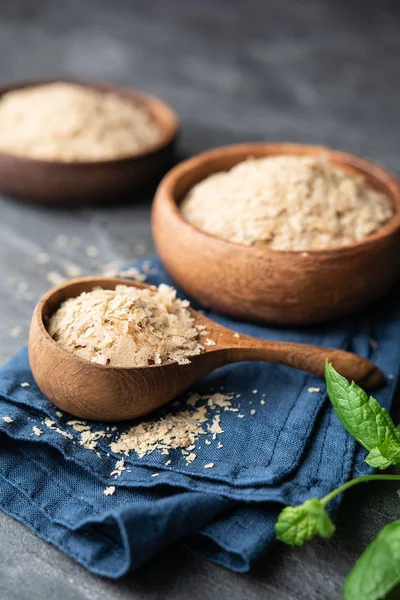 Suplemento dietético, copos de levadura nutricional sin fortificar en un tazón de madera y cuchara —  Fotos de Stock