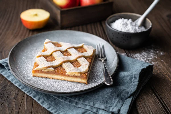 Apple cinnamon pie slice with lattice top sprinkled with powdered sugar