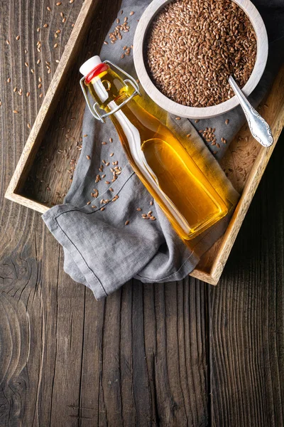 Flaxseed oil in a glass bottle, decorated with whole seeds with copy space — Stock Photo, Image