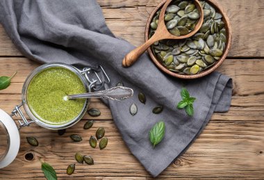 Mineraller açısından zengin sağlıklı atıştırmalıklar, ahşap arka planda cam kavanozda taze yapılmış kabak çekirdeği tohumu yağı.