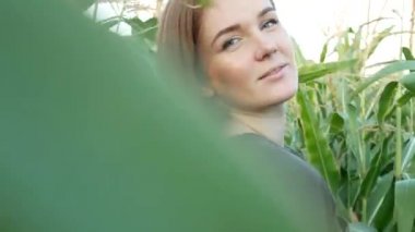 Mısır tarlasında mavi gözlü gülümseyen güzel bir kızın portresi. Gün batımında haki sweatshirt'lü tatlı genç kadın. Tarımsal Görüntüler.