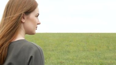 Bir çayır arka plan üzerinde haki sweatshirt düz kırmızı saçlı güzel bir kız portresi. Genç kadın yüzünün yan görünümü