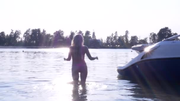 Сексуальная блондинка в розовом бикини в озере на закате — стоковое видео