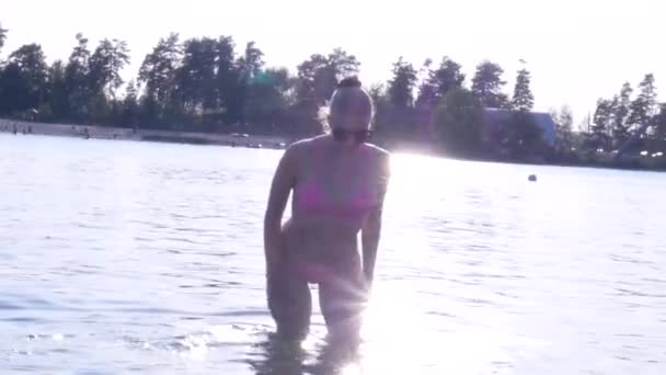 Сексуальная блондинка в бикини в озере на закате — стоковое видео