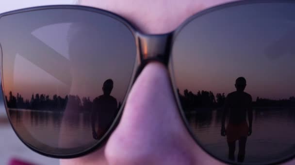 Reflejo de un hombre acercándose en gafas de sol femeninas — Vídeo de stock