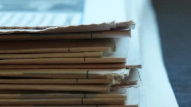 Erkek eli dikkatlice gazeteyi bir yığından topluyor. Gazetenin birikme sinin yakın çekimi. Gazete yığını yan görünüm