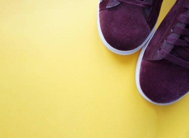 Sarı arka planda mor spor ayakkabılar.