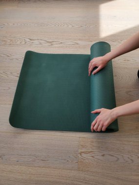 Yeşil yoga ya da spor paspası kullanan genç bir kadının elleri. Sağlıklı yaşam tarzı kavramı, kopyalama alanı.