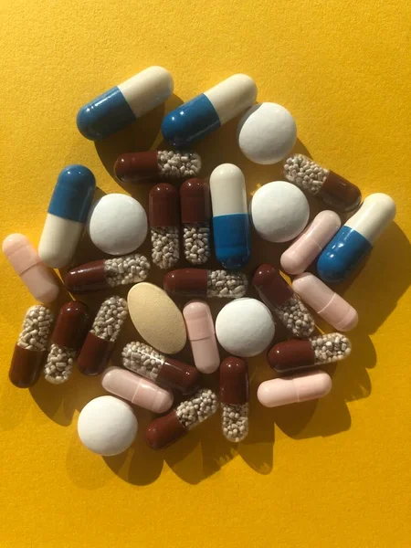 Sarı arka planda bir sürü renkli hap var. Sağlık hizmetleri kavramı.