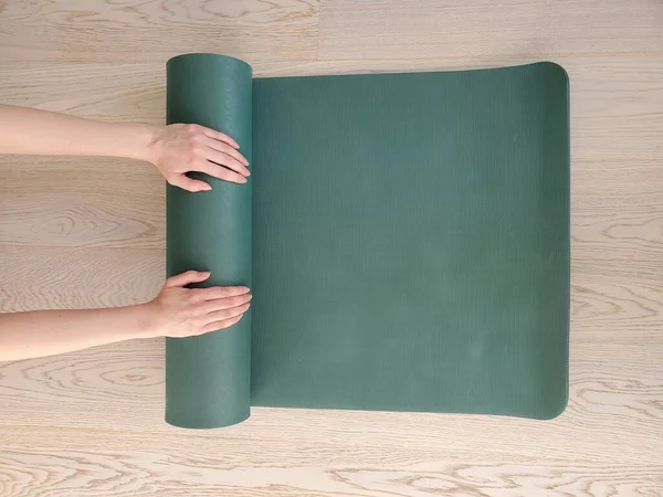 Yeşil yoga ya da spor paspası kullanan genç bir kadının elleri. Sağlıklı yaşam tarzı kavramı, kopyalama alanı.