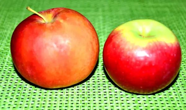 yeşil bir arka plan üzerinde iki elma