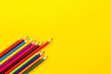 sarı arkaplanda renkli kalemler.