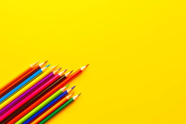 sarı arkaplanda renkli kalemler.