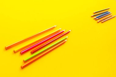 Sarı arka plan üzerinde renkli parlak kalemler.