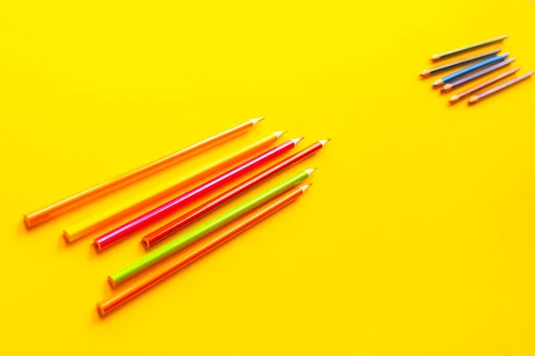 Sarı arka plan üzerinde renkli parlak kalemler.